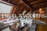 This stunning attic apartment boasts a spacious living area with exposed wooden beams and skylights, creating a bright and airy atmosphere.