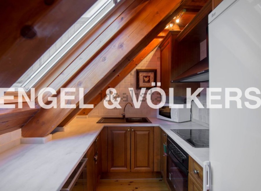 Charming attic kitchen with wooden beams and skylights.