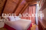 Charming attic bedroom with wooden beams and red and white striped curtains.