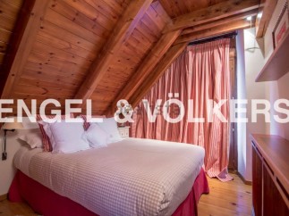 Charming attic bedroom with wooden beams and red and white striped curtains.