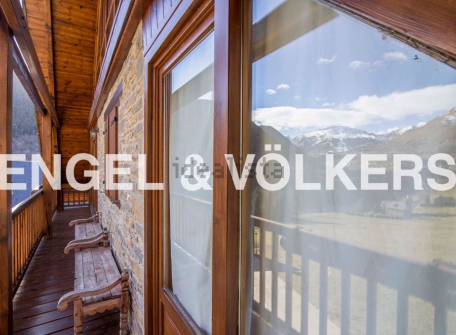 Mountain view chalet with wooden balcony and wooden benches.