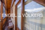 Mountain view chalet with wooden balcony and wooden benches.