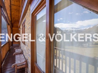 Mountain view chalet with wooden balcony and wooden benches.