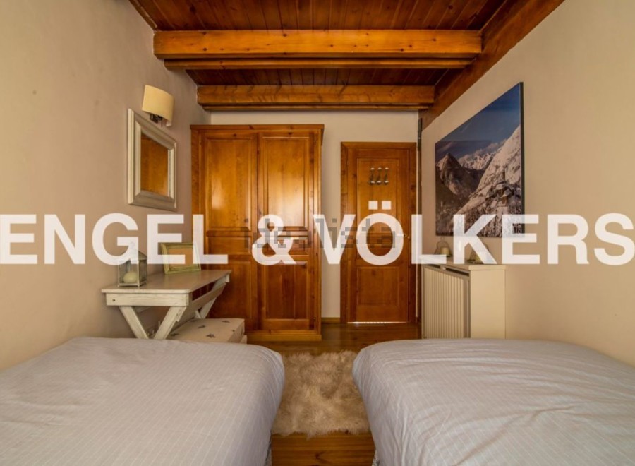 Charming chalet bedroom with twin beds, wooden wardrobe, and mountain views.