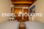 Charming chalet bedroom with twin beds, wooden wardrobe, and mountain views.