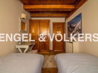 Charming chalet bedroom with twin beds, wooden wardrobe, and mountain views.