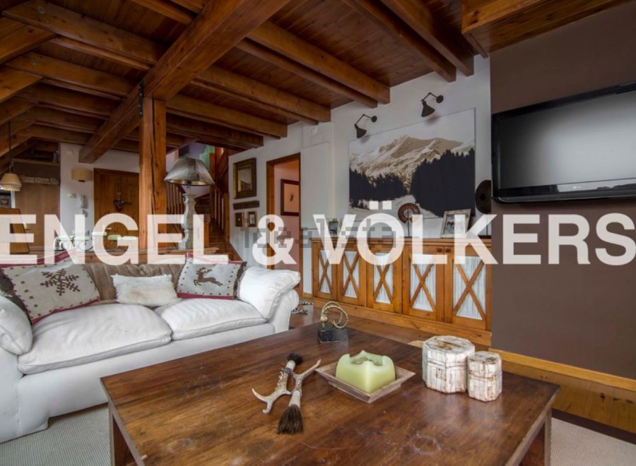 This stunning chalet boasts a spacious living area with exposed wooden beams, creating a warm and inviting atmosphere.