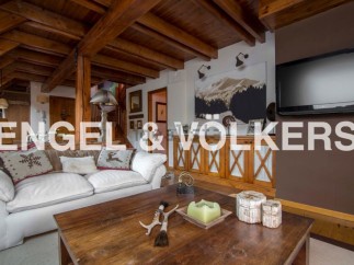 This stunning chalet boasts a spacious living area with exposed wooden beams, creating a warm and inviting atmosphere.