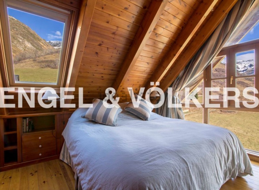 Mountain view bedroom with wooden beams and large windows.