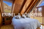 Mountain view bedroom with wooden beams and large windows.