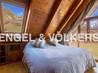 Mountain view bedroom with wooden beams and large windows.