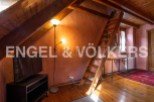 Charming attic room with wooden beams, exposed brick walls, and a wooden ladder leading to a loft.