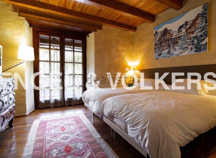 Charming rustic bedroom with twin beds, wooden beams, and large windows offering ample natural light.