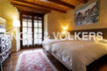 Charming rustic bedroom with twin beds, wooden beams, and large windows offering ample natural light.