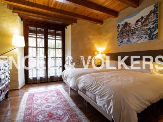Charming rustic bedroom with twin beds, wooden beams, and large windows offering ample natural light.