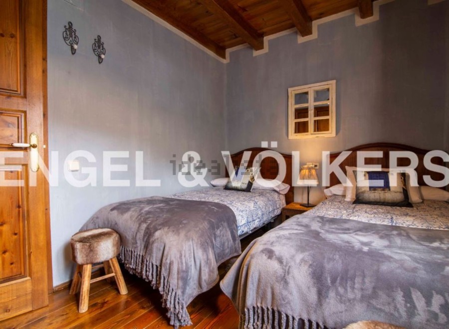 Charming rustic bedroom with twin beds, featuring wooden floors and beamed ceilings.