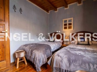 Charming rustic bedroom with twin beds, featuring wooden floors and beamed ceilings.