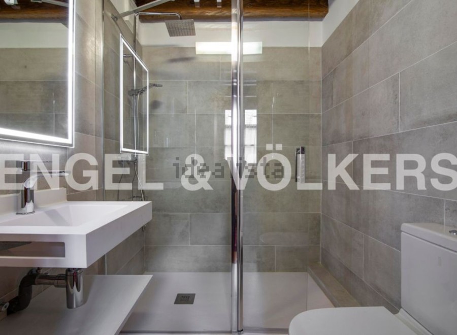 Modern bathroom with sleek, gray tile and a glass shower enclosure.