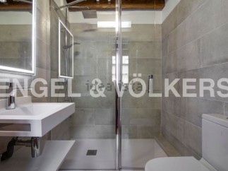 Modern bathroom with sleek, gray tile and a glass shower enclosure.