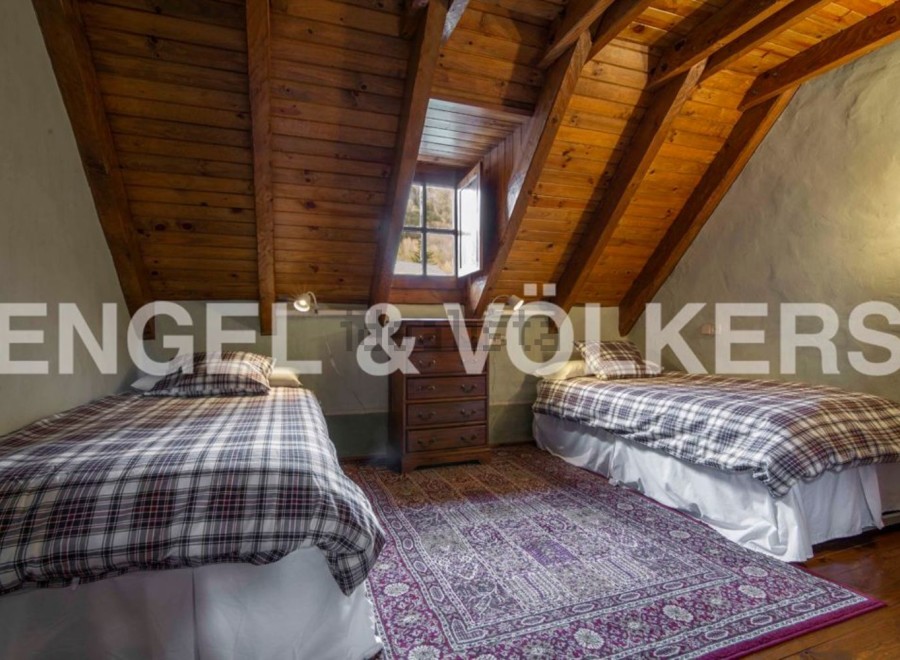 Charming attic bedroom with twin beds, wooden beams, and a cozy atmosphere.