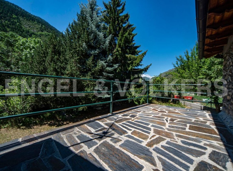 Mountain view balcony with stone tile flooring and metal railing.