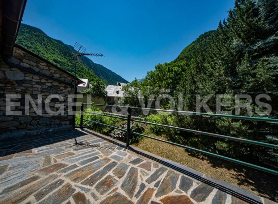 Mountain view balcony with stone flooring and metal railing.