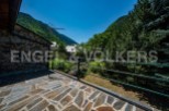 Mountain view balcony with stone flooring and metal railing.