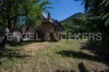 Mountainside stone house with large grassy yard and mountain views.
