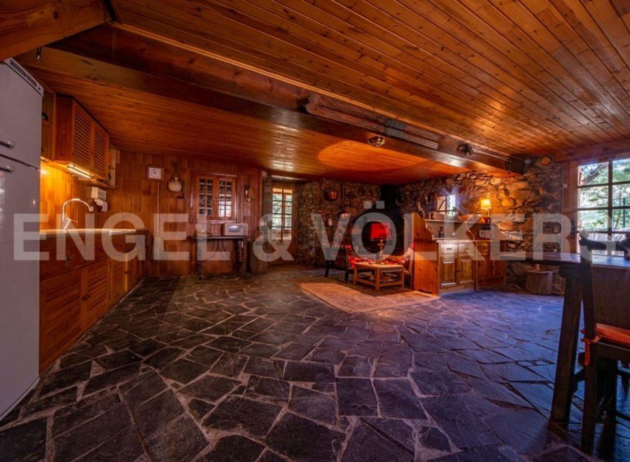 Rustic mountain cabin with stone and wood interior, featuring an open floor plan combining kitchen, living, and dining areas.