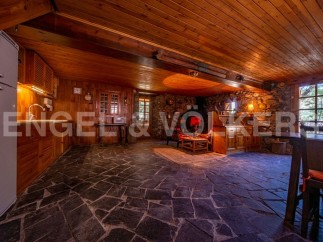 Rustic mountain cabin with stone and wood interior, featuring an open floor plan combining kitchen, living, and dining areas.