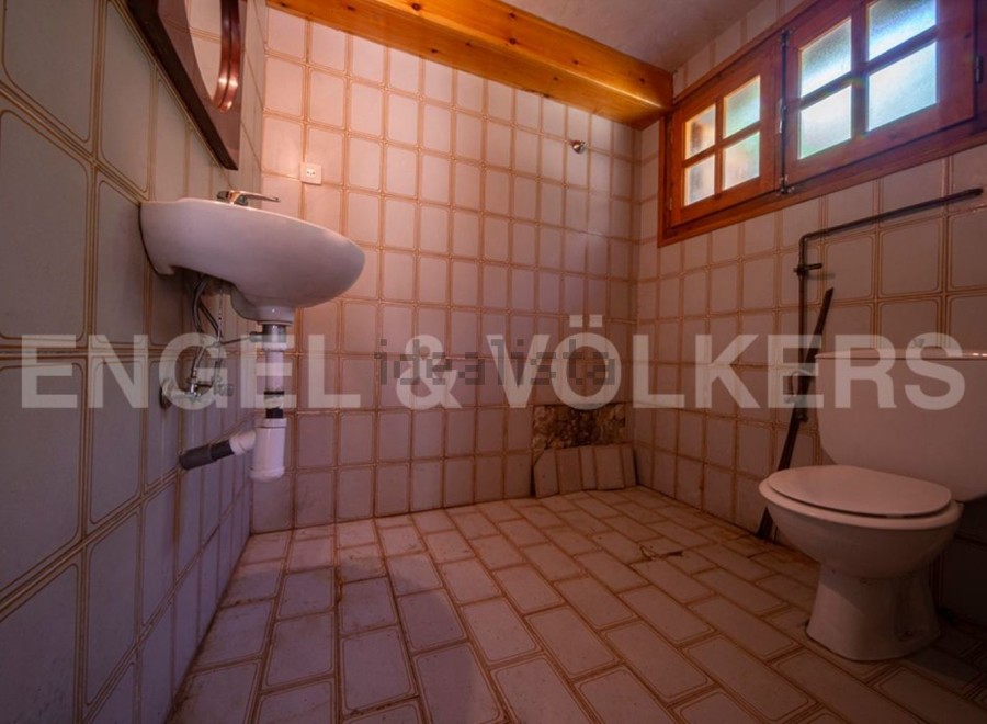 This rustic bathroom features vintage tiled walls and floors, adding to its unique charm.