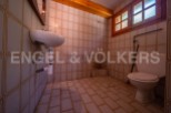 This rustic bathroom features vintage tiled walls and floors, adding to its unique charm.