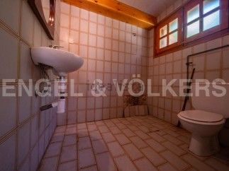 This rustic bathroom features vintage tiled walls and floors, adding to its unique charm.