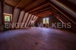 Spacious attic room with wooden beams and flooring, offering ample storage or living space.
