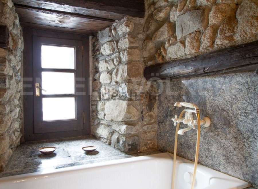 Rustic bathroom with stone walls and a vintage bathtub.