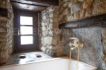 Rustic bathroom with stone walls and a vintage bathtub.