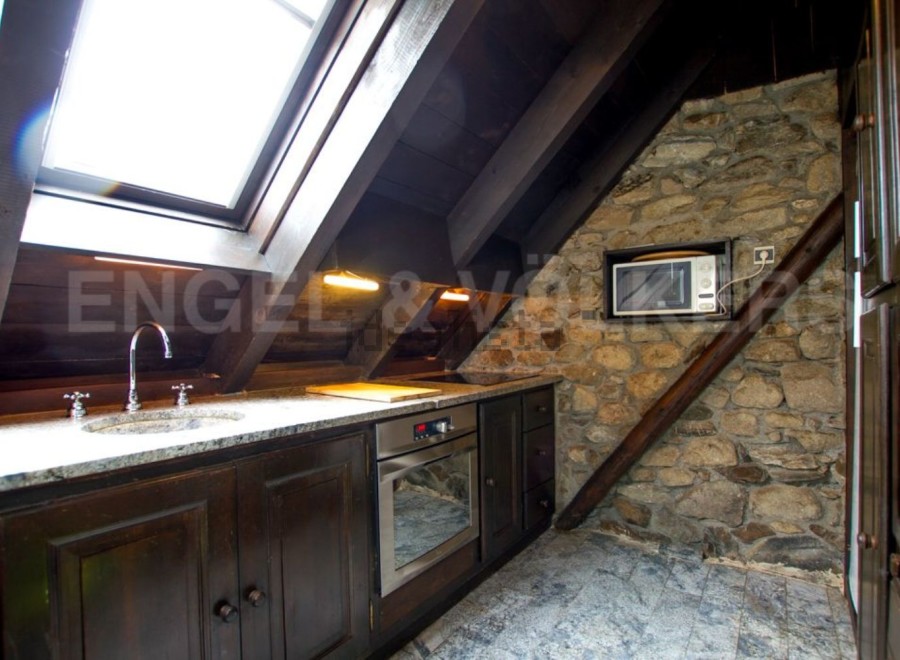 Charming attic kitchen with exposed stone wall and wood beams.