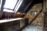 Charming attic kitchen with exposed stone wall and wood beams.