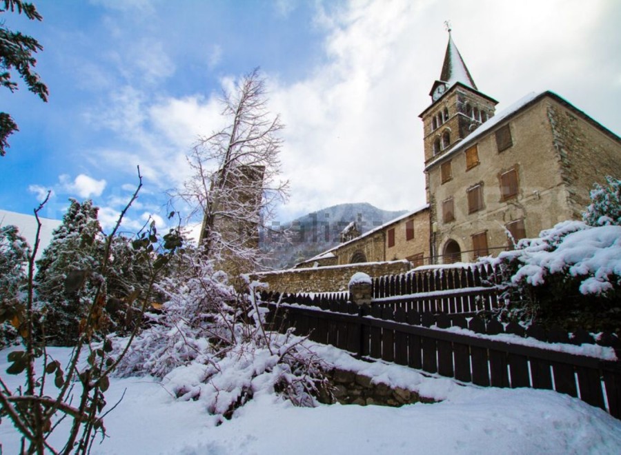 This charming church nestled in a snowy mountain village offers a picturesque winter scene.