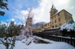 This charming church nestled in a snowy mountain village offers a picturesque winter scene.