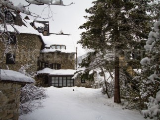 This charming stone house is nestled in a snowy winter wonderland, offering a cozy retreat.