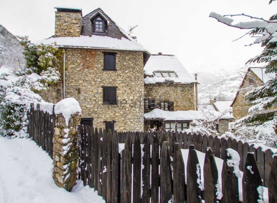 Charming stone house nestled in a snow-covered village, offering a picturesque winter escape.