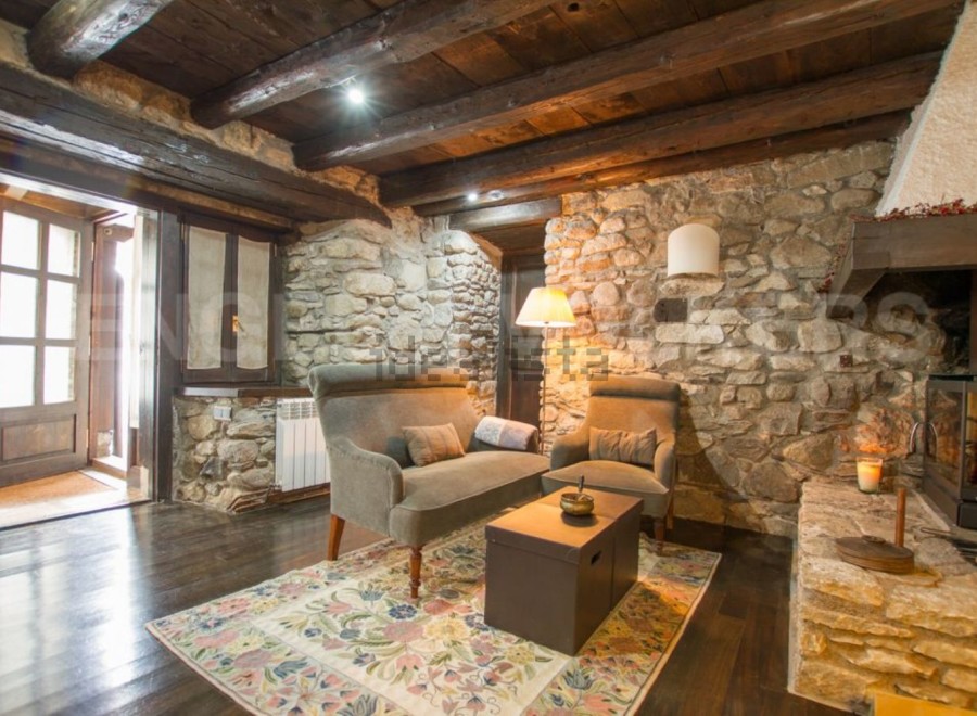 Rustic stone cottage with exposed wooden beams and a cozy fireplace.