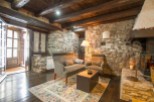 Rustic stone cottage with exposed wooden beams and a cozy fireplace.