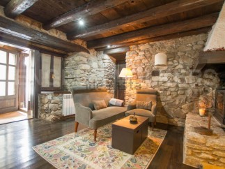 Rustic stone cottage with exposed wooden beams and a cozy fireplace.