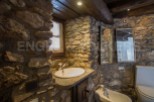 Rustic bathroom with stone walls and wooden beams.