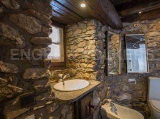 Rustic bathroom with stone walls and wooden beams.