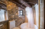 Rustic bathroom with stone walls and wooden beams.