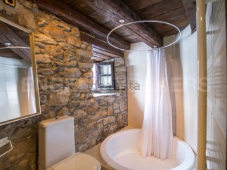 Rustic bathroom with stone walls and wooden beams.
