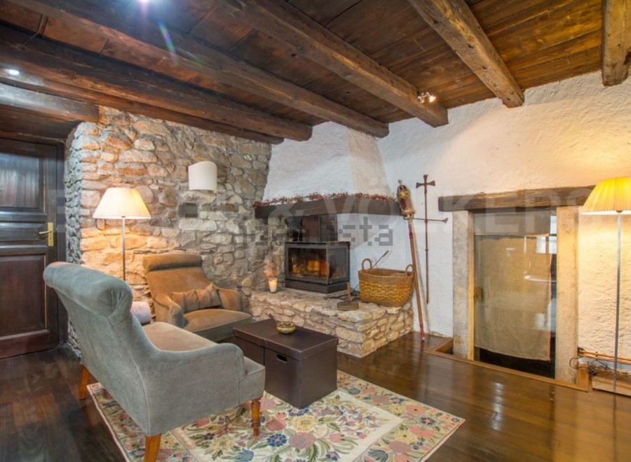 Rustic living room with stone walls, wooden beams, and a cozy fireplace.